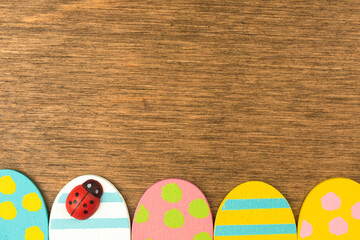 Colorful Easter eggs bottom border, old rustic wood background, flat lay design, top view with copy space photo