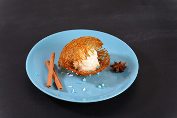 Ice cream in sugar caramel on a blue plate.