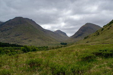Green and brown mountains in Scottish highlands with cloudy and overcast gray sky