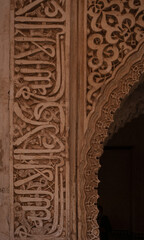 Vertical picture of arabic writing in a wall on the Alhambra, Granada, Spain. Phrases and poems 
sculptured on the wall.