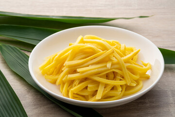 Close up sliced yellow Pickled bamboo shoots on white plate