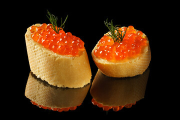 Slices of bread with red caviar on dark background.