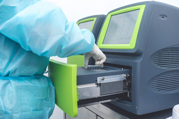 A Medical technician places Covid-19 test samples into a PCR Machine, also known a Thermal Cycler,...