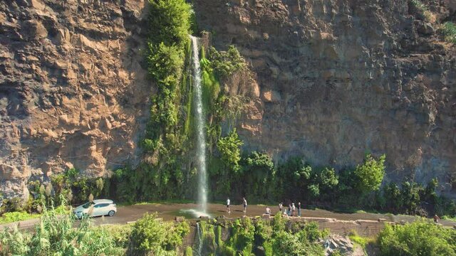 Aerial 4K footage of a drone flight over Angels waterfall (Cascata dos Anjos) in Madeira island. The waterfall cascades over the rockface onto the regional roadway, and spills into the sea below