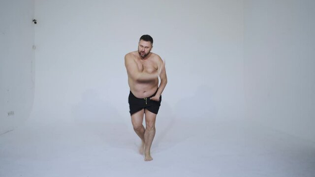 man posing for a male edition body positive beauty set. Shirtless guy wearing boxers underwear and make a funny dance