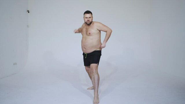 man posing for a male edition body positive beauty set. Shirtless guy wearing boxers underwear and make a funny dance