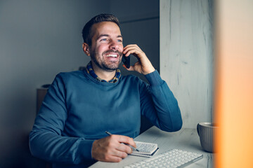 Remote job and work from home. A happy businessman is sitting at his home office, having a call...