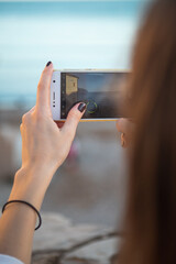 woman taking photo with smartphone at seaside.