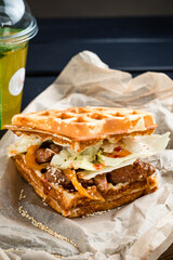Waffle sandwich with meat and vegetables on wooden table background