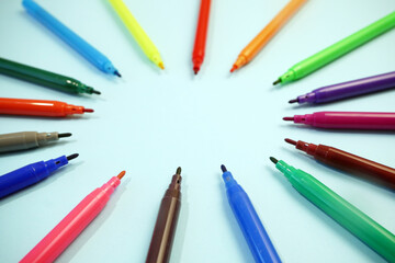 many colorful markers facing the center on blue, good template for your creative idea, copy space