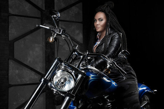girl on a motorcycle. black long hair. a dark room