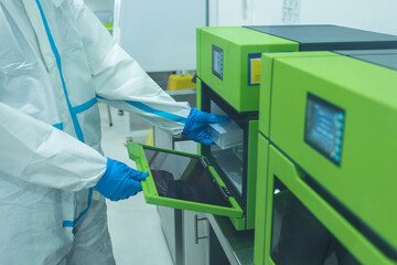 A lab technician places RT-PCR test samples into a DNA or RNA extraction machine. At a testing...