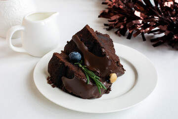 Chocolate brownie cake (fudge brownie), decorated with nut, blueberry and rosemary twig, on white...