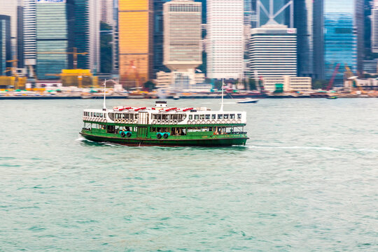 Landscape of Victoria Harbor and Hong Kong's iconic Star Ferry making its way across a cloudy Victoria Harbour.