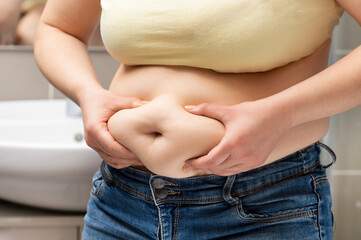 Close up of a obese young woman checking her fats in the bathroom