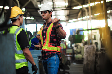 Dark tall and handsome Asian Professional engineering man are training and coaching the technician Machine operator control and checking operating in factory. safety first concept.
