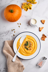 Pumpkin traditional soup with creamy silky texture with sage leaves and red pepper in white plate or bowl. Light grey background. Copy space. Mock up. Top view, flat lay.
