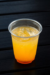 Orange soda drink with ice cubes in take away cup, cold orange lemonade in a plastic cup