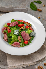 Nutritious salad of hot bacon, pieces of beef, dorblu cheese, walnuts and tomatoes.