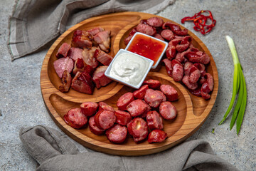 Meat appetizers of baked pork ribs with homemade fried potatoes, pickles and sliced sausages.