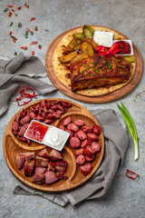 Meat appetizers of baked pork ribs with homemade fried potatoes, pickles and sliced sausages.