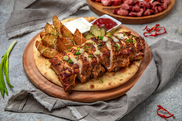 Meat appetizers of baked pork ribs with homemade fried potatoes, pickles and sliced sausages.
