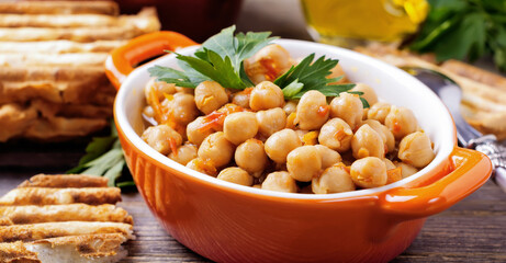 Vegetarian cooked chickpea with tomato and parsley on old wooden background. Selective focus.
