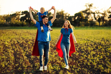 Fototapeta premium concept of european superfamily, outdoors, loving father holds on the neck, superhero family run at sunset in nature