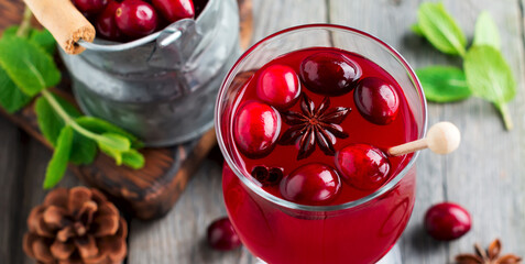 Fresh cranberry juice with cinnamon and anise in glass jars on the old wooden background. Selective focus.Top view.