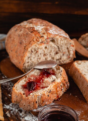 Sliced rye bread with apple jam on a wooden board. Side view.