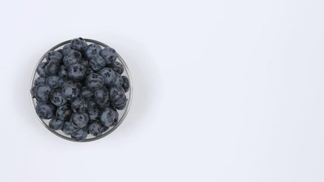 Blueberries in a glass bowl on a white background. Top view. Loop motion. Free space on the right. Rotation 360. 4K UHD video footage 3840X2160.