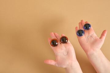cute face from the hands of a child, children's hand and doll plastic eyes, painted smiles, sad and cheerful monsters