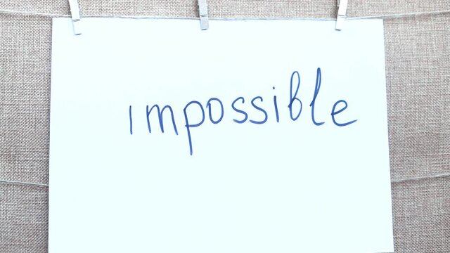 woman's hand erases im and get an inscription possible instead of impossible on white sheet of paper.