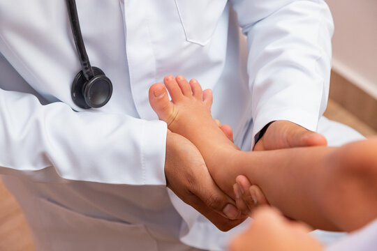 doctor examining children's feet in hospital. Surgeon, traumatologist or orthopedist palpating girl's leg and foot