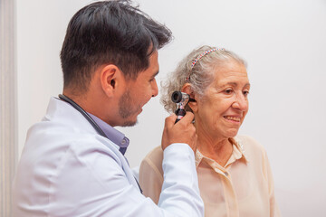Doctor examining ear of elderly female with otoscope in clinic