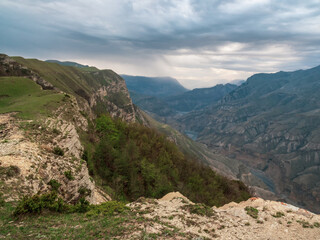 Colorful rainy landscape with cliff and big rocky mountains and epic deep gorge. High stone peaks of Dagestan mountains.