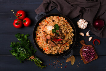 Uzbek pilaf, stewed rice with meat, in a cast-iron cauldron, on a dark gray wooden table, top view, no people, toned,