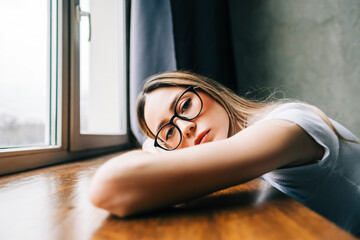 Young bored millennial woman on windowsill alone at home. Fatigue or emotionally exhausted concept