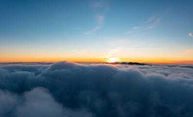 Thick layer of white clouds above mountains at sunrise