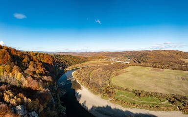River rapids with autumn forests on banks under blue sky