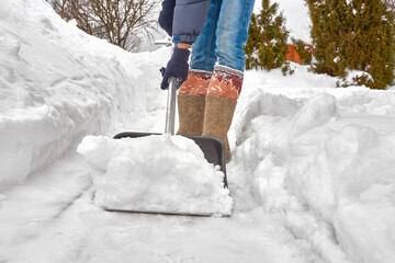 A man in felt boots removes snow with a shovel.
