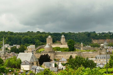 
Vue panoramique sur le château dominant la vieille ville de Fougères sous un ciel sombre
