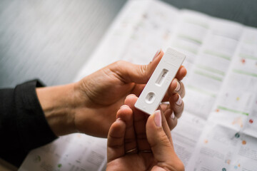Close up photography woman's hand holding a negative result of auto test antigen covid. Instructions at the background.