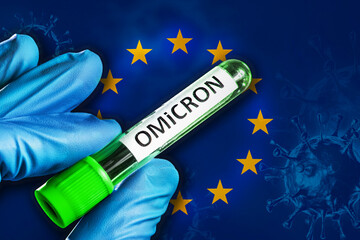 EU outbreak of omicron variant. Hand holds a test tube with covid-19 virus omicron in front of EU...