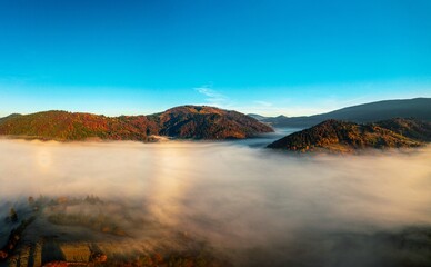 Thick layer of fog covering rainbow mountains with colorful trees