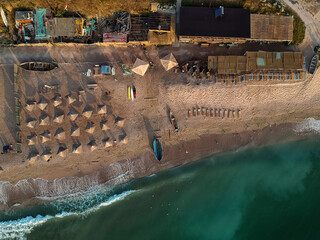 Aerial view of amazing beach with umbrellas and turquoise sea at sunrise. Black Sea at Vama Veche, Romania