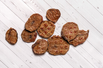 Some cut pieces of dehydrated beef treats for pets, bull testicles. Dry dog food, home-made and natural stuff. White background, close up, copy space.