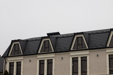 The roof of the house is made of red metal tiles, a beautiful large chimney
