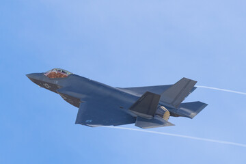 Fototapeta na wymiar Close side view of a F-35C in beautiful light, with condensation trails at the wing tips