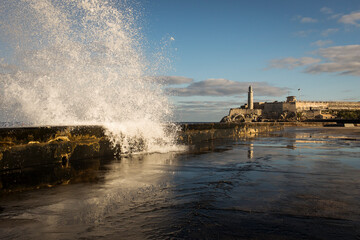 Big waves on Malecon streets during sunrise with storm clouds in background. Havana, Cuba